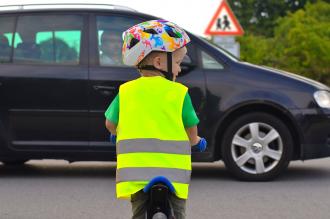 A child riding a bike with a helmet and hi-vis jacket on approaching a car with the driver looking on - credit: Derbyshire PCC's office